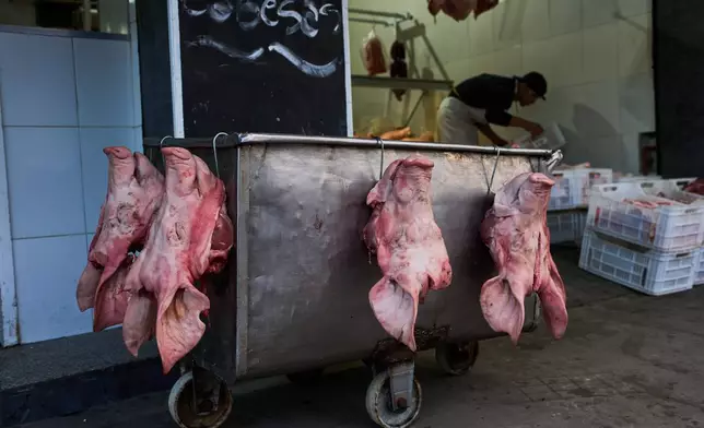 Pig heads hang outside a butcher shop for sale at the Mataderos meat market in Buenos Aires, Argentina, Thursday, May 14, 2026. (AP Photo/Rodrigo Abd)