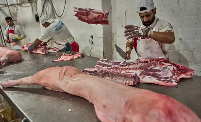 A worker cuts pork at the Mataderos meat market in Buenos Aires, Argentina, Thursday, May 14, 2026. (AP Photo/Rodrigo Abd)