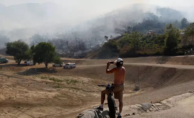 A resident uses a smartphone as the Sandy Fire approaches, Tuesday, May 19, 2026, in Simi Valley, Calif. (AP Photo/Caroline Brehman)