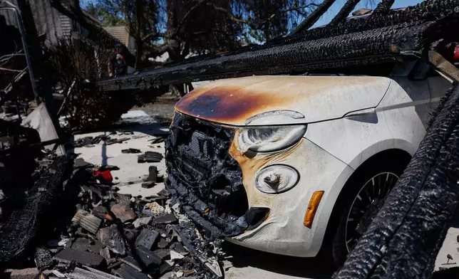 A charred vehicle sits under debris during wildfires, Tuesday, May 19, 2026, in Simi Valley, Calif. (AP Photo/Caroline Brehman)