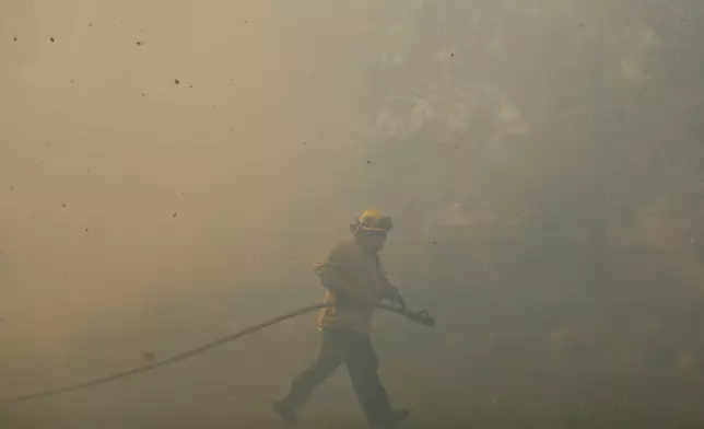 A firefighter works as the Sandy Fire approaches, Tuesday, May 19, 2026, in Simi Valley, Calif. (AP Photo/Caroline Brehman)