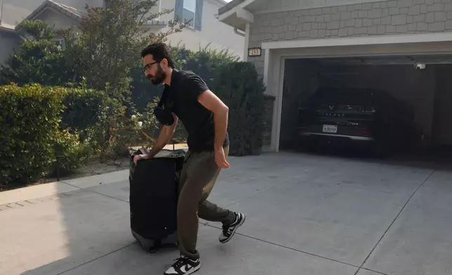 A resident evacuates during as the Sandy Fire approaches, Tuesday, May 19, 2026, in Simi Valley, Calif. (AP Photo/Caroline Brehman)