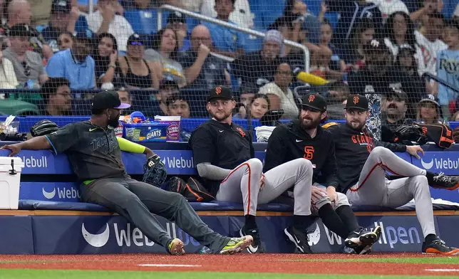 Tampa Bay Rays third baseman Junior Caminero, left, sits on the San Francisco Giants bullpen bench after chasing a foul ball by Luis Arraez during the sixth inning of a baseball game Saturday, May 2, 2026, in St. Petersburg, Fla. (AP Photo/Chris O'Meara)