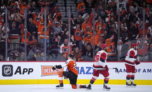 Philadelphia Flyers' Alex Bump, left, celebrates past Carolina Hurricanes' Jordan Martinook, center, and Sean Walker, right, after scoring a goal during the third period of Game 4 in a second-round NHL hockey Stanley Cup playoff series Saturday, May 9, 2026, in Philadelphia. (AP Photo/Matt Slocum)