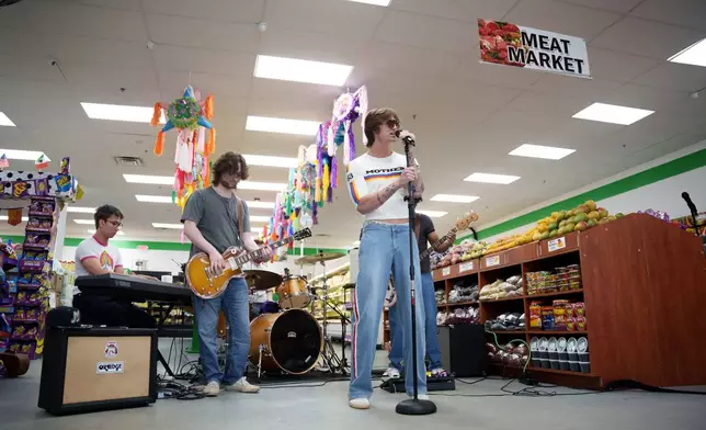 Singer Jackson Laird, right, performs with bandmates Gabriel Schauf and Tanner Kelley in the produce section of Fiesta Fresh Market in New Castle, Del., on Sunday, April 26, 2026. (AP Photo/Mingson Lau)