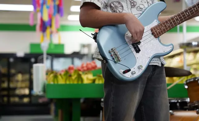 A guitarist performs in the produce section of Fiesta Fresh Market in New Castle, Del., on Sunday, April 26, 2026. (AP Photo/Mingson Lau)