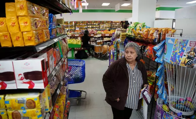 A woman shops while a band plays in the background in New Castle, Del., on Sunday, April 26, 2026. (AP Photo/Mingson Lau)