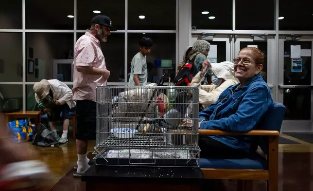 Angie Mallon, an evacuee from an aerospace chemical plant tank leak, exits the Garden Grove Sports and Recreation Center with her pet pigeon in Garden Grove, Calif., Friday, May 22, 2026. (AP Photo/Ethan Swope)