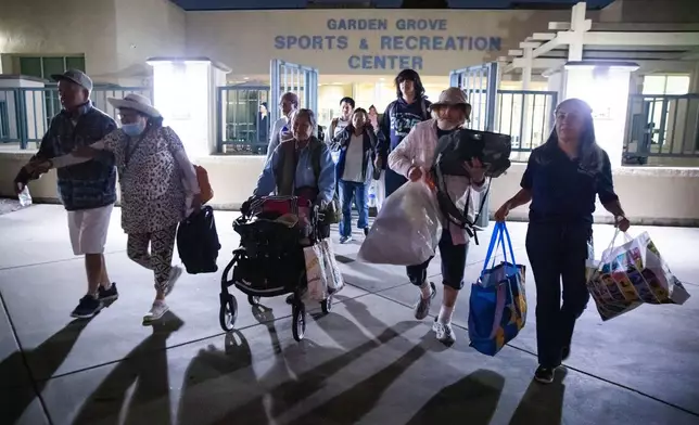 Evacuees from an aerospace chemical plant tank leak move to another shelter after the Garden Grove Sports and Recreation Center closed for the night in Garden Grove, Calif., Friday, May 22, 2026. (AP Photo/Ethan Swope)