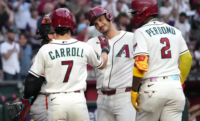 Arizona Diamondbacks' Nolan Arenado, second from right, celebrates with Corbin Carroll (7) and Geraldo Perdomo (2) after hitting a grand slam against the San Francisco Giants in the first inning of a baseball game, Monday, May 18, 2026, in Phoenix. (AP Photo/Rick Scuteri)
