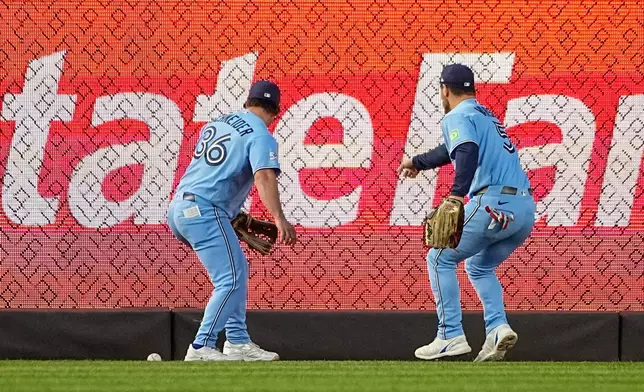Toronto Blue Jays outfielders Davis Schneider (36) and Daulton Varsho (5) try to reach the ball during the second inning of a baseball game against the New York Yankees, Thursday, May 21, 2026. in New York. (AP Photo/Eduardo Munoz Alvarez)