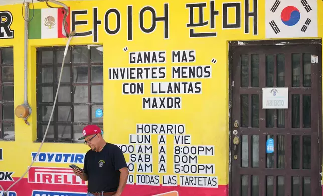 Small business owner Mario Alberto Cantú stands outside his tire repair shop, with words in both Spanish and Korean displayed across the storefront in Pesqueria, Mexico, Tuesday, March 31, 2026. (AP Photo/Fernando Llano)