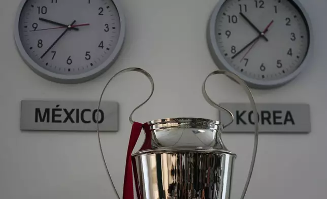 A replica of the UEFA Champions trophy is displayed next to clocks with the local time and Korea time at the Kia motors headquarters in Pesqueria, Mexico, Tuesday, March 31, 2026. (APPhoto/Fernando Llano)