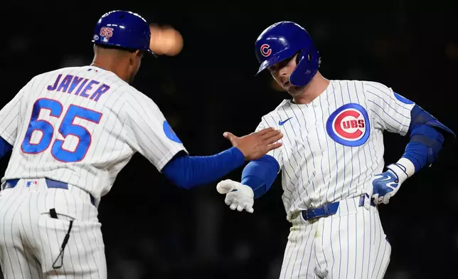 Chicago Cubs' Nico Hoerner, right, celebrates with first base coach Jose Javier, left, after hitting a one-run single during the eighth inning of a baseball game against the Milwaukee Brewers in Chicago, Tuesday, May 19, 2026. (AP Photo/Nam Y. Huh)
