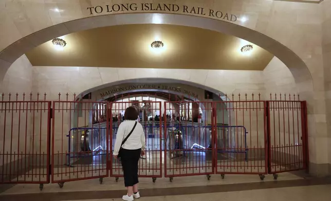 A passenger looks at a closed off entrance to the Long Island Rail Road at Grand Central station, Saturday, May 16, 2026, in New York, on the first day of a strike after five unions representing about half the LIRR's workforce walked off the job. (AP Photo/Heather Khalifa)