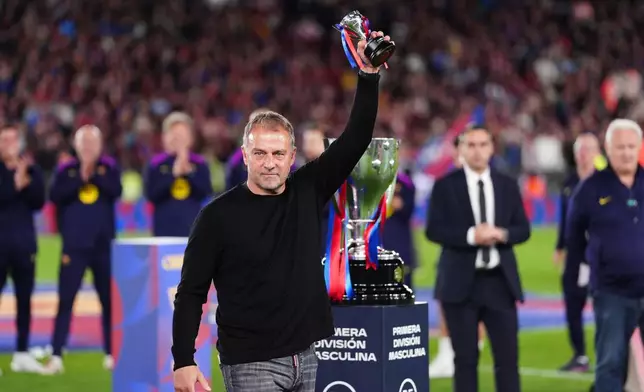 Barcelona head coach Hansi Flick lifts his award to the sky celebrating after defeating Real Madrid 2-0 to win the Spanish La Liga soccer championship with three rounds to spare, in Barcelona, Spain, Sunday, May 10, 2026. (AP Photo/Joan Mateu Parra)