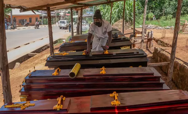 Djakisa Christian, 18, a funeral home manager, dusts coffins for sale at his shop in Bunia, Congo, Friday, May 22, 2026. (AP Photo/Moses Sawasawa)