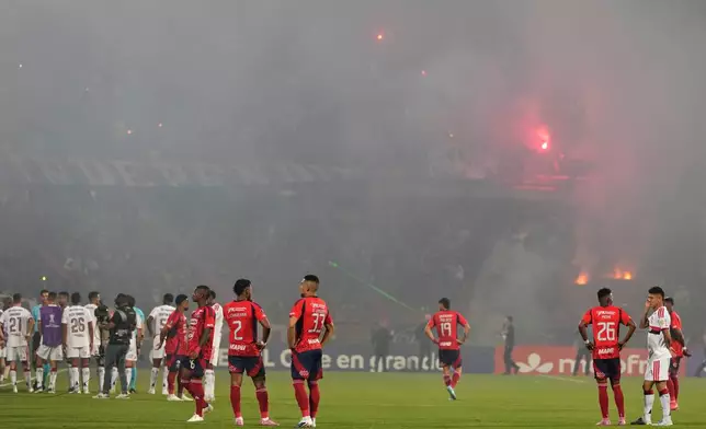 Players of Colombia's Independiente Medellin and Brazil's Flamengo stand on the field after the match was temporarily suspended because of crowd trouble during a Copa Libertadores Group A soccer match in Medellin, Colombia, Thursday, May 7, 2026. (AP Photo/Fernando Vergara)