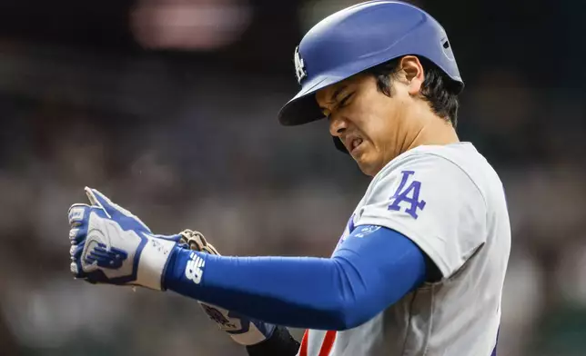 Los Angeles Dodgers two-way player Shohei Ohtani adjusts his gloves at first base during the first inning of a baseball game against the Milwaukee Brewers, Friday, May 22, 2026, in Milwaukee. (AP Photo/Jeffrey Phelps)