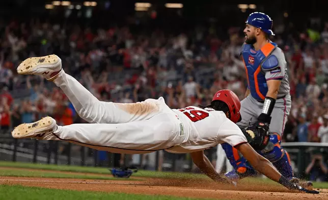 Washington Nationals' James Wood slides into home as New York Mets catcher Luis Torrens waits for the throw on an inside the park gland slam home run during the second inning of a baseball game Tuesday, May 19, 2026, in Washington. (AP Photo/John McDonnell)