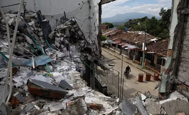 A man rides his motorcycle past the ruins of homes destroyed five months earlier in an attack by dissidents of the former Revolutionary Armed Forces of Colombia, or FARC, in Buenos Aires, Cauca, Colombia, Wednesday, May 20, 2026.(AP Photo/Santiago Saldarriaga)
