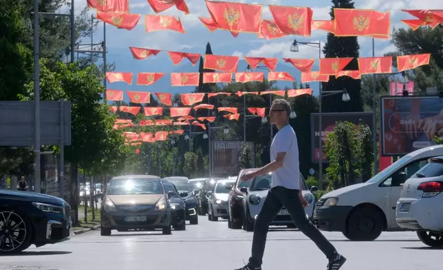 A man walks on a street decorated with national flags in Montenegro's capital Podgorica, Monday, May 18, 2026. (AP Photo/Risto Bozovic)