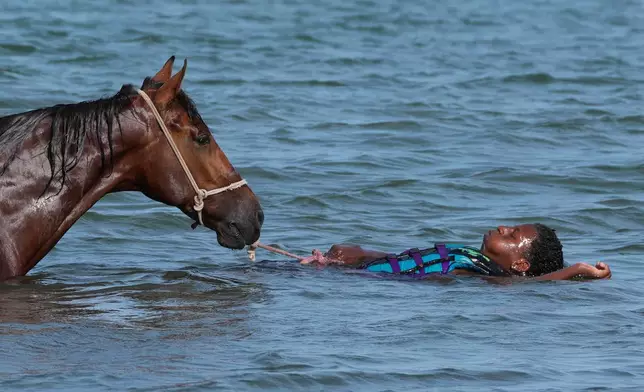 A man swims in the sea with his horse in Praia, Cape Verde, Thursday, May 7, 2026. (AP Photo/Misper Apawu)