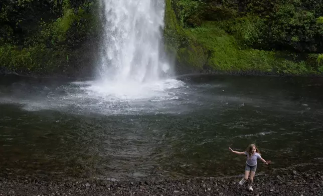 A child runs on rocks after touching the water at Horsetail Falls on Saturday, May 2, 2026, in the Columbia River Gorge, Ore. (AP Photo/Jenny Kane)