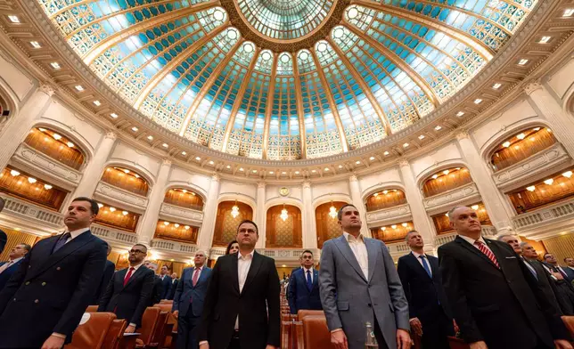 Romanian lawmakers stand during the anthem ahead of a no confidence vote against Prime Minister Ilie Bolojan's government in Romania's parliament in Bucharest, Romania, Tuesday, May 5, 2026. (AP Photo/Vadim Ghirda)