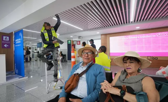 A worker paints the ceiling during a guided media tour of the renovation work at Benito Juárez International Airport, in preparation for the 2026 World Cup, as passengers await their flights in Mexico City, Tuesday, May 19, 2026. (AP Photo/Fernando Llano)