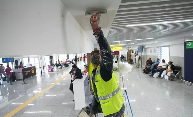 A worker paints the ceiling in Terminal 1 during a guided media tour of the renovation work at Benito Juárez International Airport, in preparation for the 2026 World Cup in Mexico City, on Tuesday, May 19, 2026. (AP Photo/Fernando Llano)