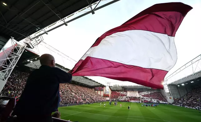 A Heart of Midlothian fan waves a large flag ahead the Scottish Premiership soccer match between Heart of Midlothian and Falkirk, Wednesday, May 13, 2026, in Edinburgh, Scotland. (Andrew Milligan/PA via AP)