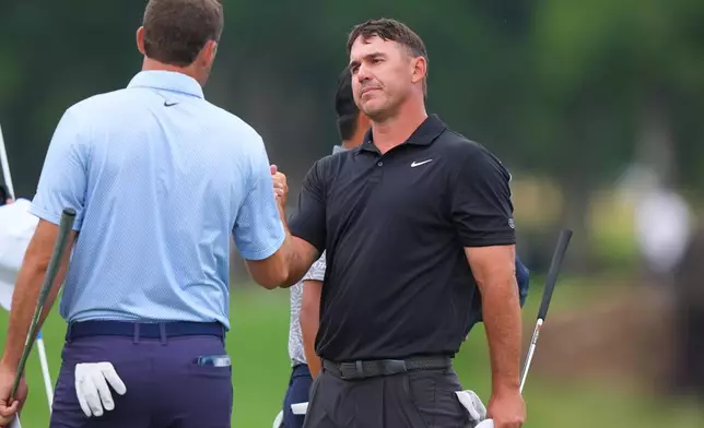 Brooks Koepka, right, shakes hands with Scottie Scheffler after playing their final hole in the first round of the Byron Nelson golf tournament in McKinney, Texas, Thursday, May 21, 2026. (AP Photo/LM Otero)