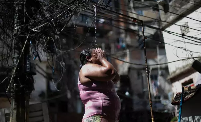 FILE - Kelly Cristina da Cruz cools off in a public shower in the Rocinha favela amid a heat wave in Rio de Janeiro, Jan. 15, 2026. (AP Photo/Bruna Prado, File)