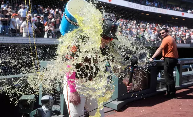 San Francisco Giants' Harrison Bader is doused by Willy Adames while being interviewed after a baseball game against the Chicago White Sox Saturday, May 23, 2026, in San Francisco. (AP Photo/Jeff Chiu)