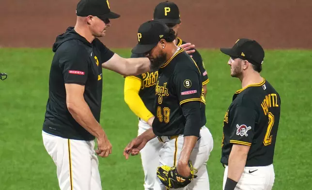 Pittsburgh Pirates pitcher Yohan Ramírez, center, walks off the mound after handing the ball to manager Don Kelly, left, during the seventh inning of a baseball game against the Chicago Cubs in Pittsburgh, Wednesday, May 27, 2026. (AP Photo/Gene J. Puskar)