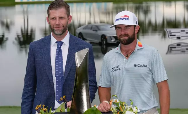 Cameron Young, right, stands with Eric Trump as he poses with the trophy after winning the Cadillac Championship PGA golf tournament Sunday, May 3, 2026, in Doral, Fla. (AP Photo/David J. Phillip)