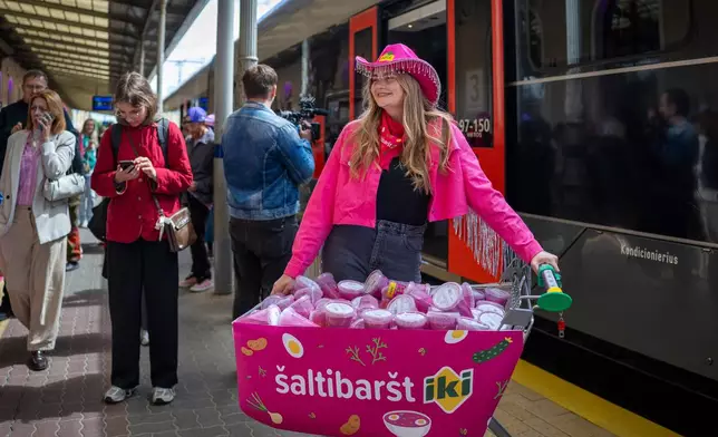 A girl ready to share Pink soup during the Pink Soup Fest celebration, on a railway station platform in Vilnius, Lithuania, Friday, May 29, 2026. (AP Photo/Mindaugas Kulbis)