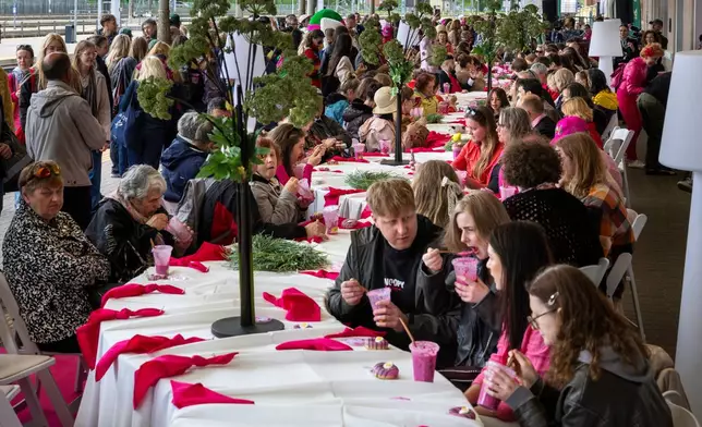 People eat pink soup during a pink break in the Pink Soup Fest celebration, on a railway station platform in Vilnius, Lithuania, Friday, May 29, 2026. (AP Photo/Mindaugas Kulbis)