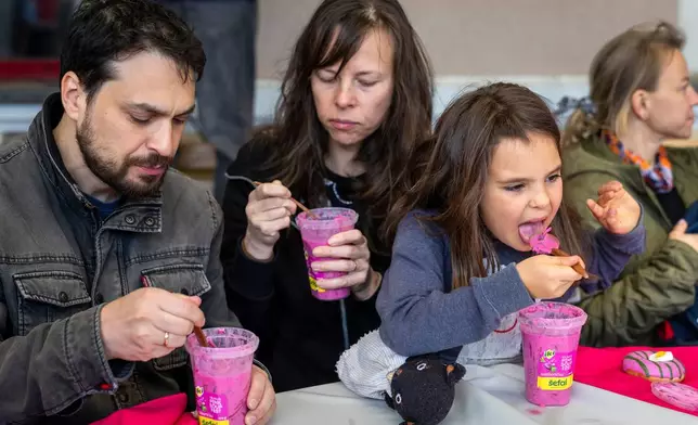 People eat pink soup during a pink break in the Pink Soup Fest celebration, on a railway station platform in Vilnius, Lithuania, Friday, May 29, 2026. (AP Photo/Mindaugas Kulbis)
