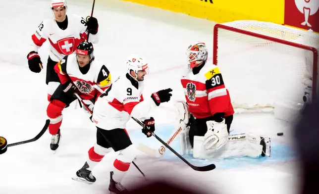 Switzerland's Theo Rochette, behind left,and Switzerland's Damien Riat, center, celebrate the fourth goal in front of Austria's Ramon Schnetzer, left, and Austria's goaltender David Kickert, right, during the 2026 IIHF Men's Ice Hockey World Championship preliminary round group A game between Austria and Switzerland, in Zurich, Switzerland, Wednesday, May 20, 2026. (Claudio Thoma/Keystone via AP)