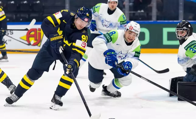 Sweden's Carl Grundstrom, left, vies for the puck against Slovenia's Marcel Mahkovec, right, during the 2026 IIHF Men's Ice Hockey World Championship preliminary round group B game between Sweden and Slovenia, in Fribourg, Switzerland, Wednesday, May 20, 2026. (Cyril Zingaro/Keystone via AP)