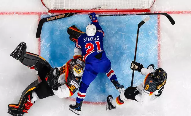 United States Alex Steeves falls in the crease between Germany's goaltender Philipp Grubauer, left, and Leon Gawanke during a Group A preliminary round game between the United States and Germany at the men's ice hockey world championship in Zurich, Switzerland, Wednesday, May 20, 2026. (Andreas Becker/Keystone via AP)