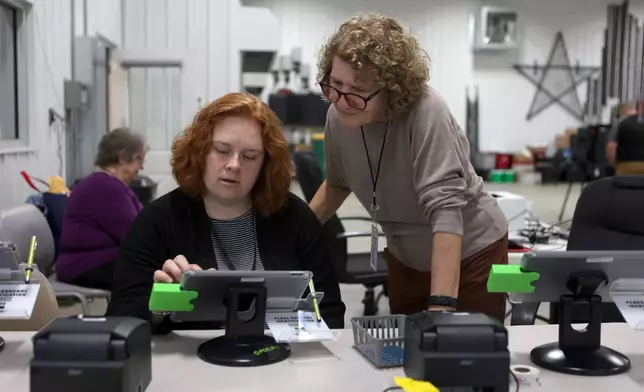 Election workers Kirsten White, left, and Angie Wilhoit, right, look at a tablet together in a vote center during a primary election on Tuesday, May 5, 2026, in West Lafayette, Ind. (AP Photo/Cara Penquite)
