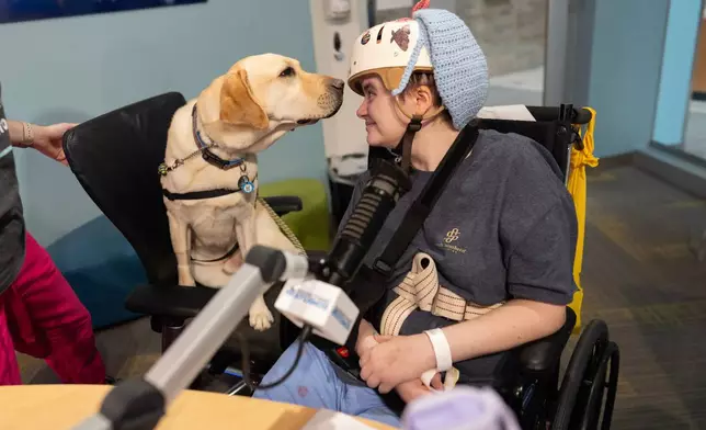 Cincinnati Children's Hospital facility dog Grover, left, looks to patient Kira Hodge at the hospital's Seacrest Studios as they produce a closed-circuit television show beamed into patient rooms, at Cincinnati Children's Hospital in Cincinnati, Monday, May 4, 2026. (AP Photo/Carolyn Kaster)
