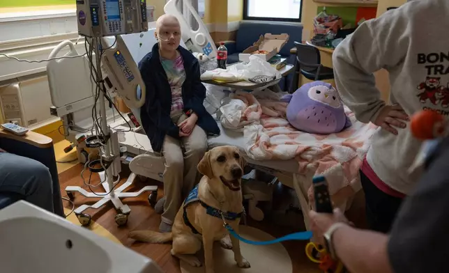 Cincinnati Children's Hospital facility dog Hadley sits at the feet of 11-year-old Bethany Striggles, who recently finished a chemotherapy treatment for bone cancer, in her room at Cincinnati Children's Hospital in Cincinnati, Monday, May 4, 2026. (AP Photo/Carolyn Kaster)