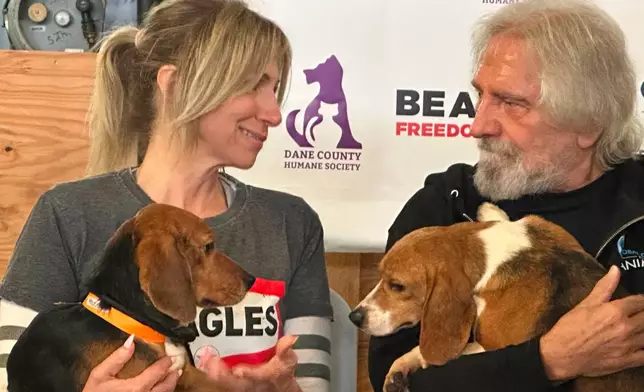 Pop star Debbie Gibson and Black Sabbath co-founder Terry "Geezer" Butler hold beagles that were purchased from a Dane County animal research facility on Tuesday, May 12, 2026, in Madison, Wis. (AP Photo/Scott Bauer)