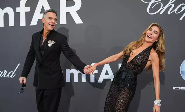 Robbie Williams, left, and Ayda Field pose for photographers upon arrival at the amfAR Cinema Against AIDS benefit at the Hotel du Cap-Eden-Roc, during the 79th Cannes international film festival, Cap d'Antibes, southern France, Thursday, May 21, 2026. (Photo by Scott A Garfitt/Invision/AP)A