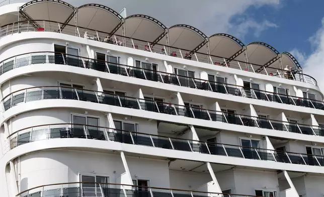 Passengers stand aboard the British cruise ship Ambition, as French authorities have ordered 1,700 passengers and crew to stay on board due to a gastrointestinal illness outbreak, in Bordeaux, southwestern France, Wednesday, May 13, 2026. (AP Photo/Caroline Blumberg)