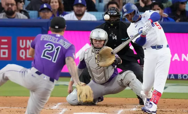 Los Angeles Dodgers' Mookie Betts, right, hits a two-run home run as Colorado Rockies pitcher Kyle Freeland, left, and catcher Hunter Goodman watch during the first inning of a baseball game Tuesday, May 26, 2026, in Los Angeles. (AP Photo/Mark J. Terrill)
